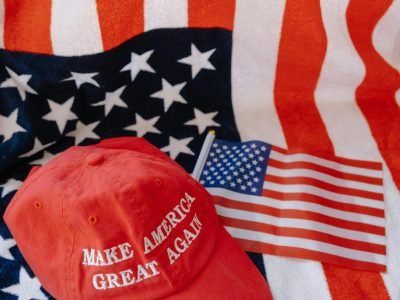 Red cap with 'Make America Great Again' text on US flag background.